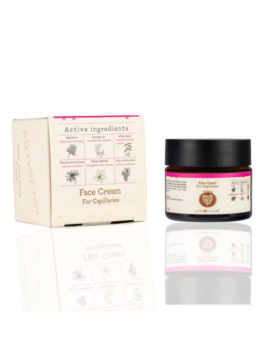 A jar of Soap&Friends Vascular Skin Soothing Natural Face Cream for Capillaries next to its packaging box. The packaging is labeled with the product name and has images representing the key ingredients like turmeric and avocado oil.