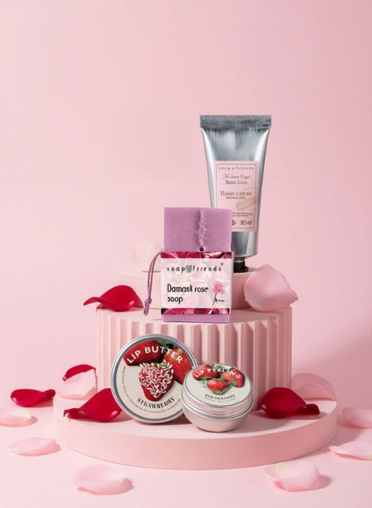 Skincare products including a tube, jar, and small containers on a pink platform with rose petals.