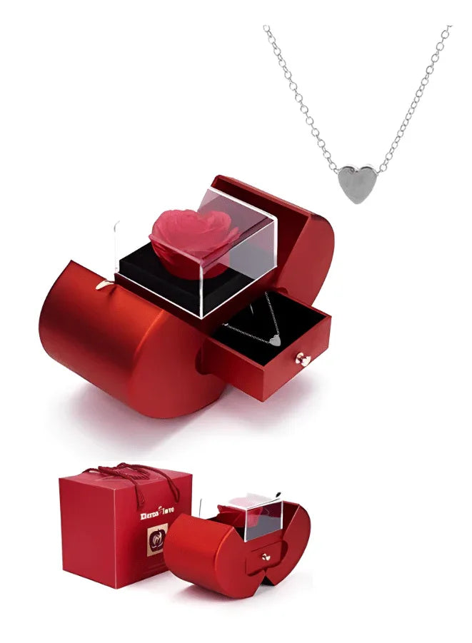 A red rose in a heart-shaped glass box with a silver necklace, indicating a romantic gift setup, likely for occasions like Valentine's Day.