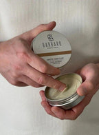 Person holding a container of Barbaro Matte Hair Clay with a neutral background