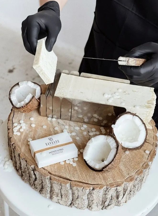 Coconut and soap display on a wooden base with a person using a tool.