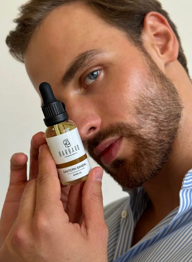 Man holding a bottle of Barbaro Beard Oils with a neutral background