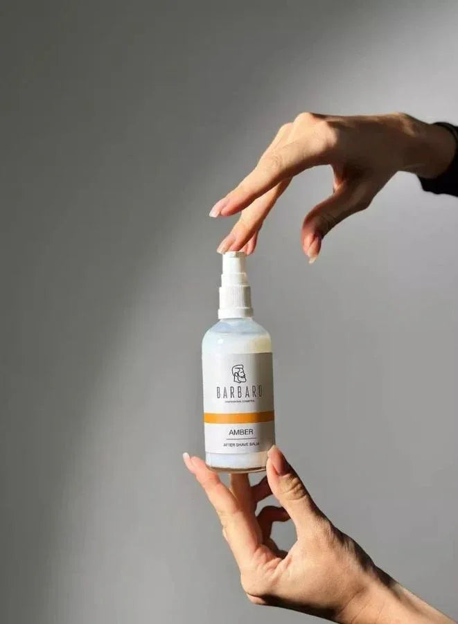 Person holding a bottle labeled 'Barbaro' against a gray background