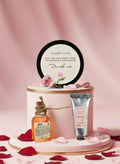 Skincare product set with a bottle, jar, and round container on a pink background with rose petals.